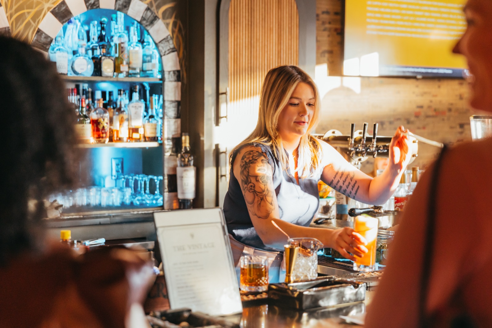 A bartender pouring a cocktail behind the bar